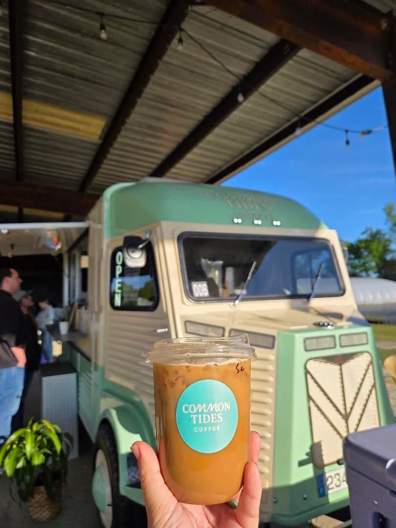 Iced latte in a Common Tides cup in front of the vintage coffee trailer at a Wilmington NC event